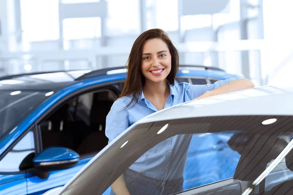 对我来说是完美的车 华丽的年轻女子微笑着愉快地靠在汽车在当地的汽车经销店 — 图库照片
