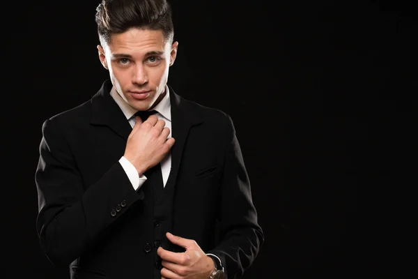 Joven Hombre Guapo Con Elegante Traje Negro Ajustando Corbata Mirando —  Fotos de Stock