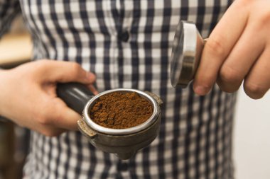 Onun kafe Cafe arabica profesyonel garson garson küçük iş rekreasyon işgal kavramı çalışma preslenmiş gound kahve ile dış müdahale ve portafilter tutan bir barista, yakın kırpılmış