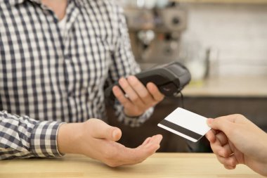 Close up cropepd shot of a female customer passing her credit card to a coffee shop worker paying for coffee banking economy money service online connectivity checkout retail shopping buyer