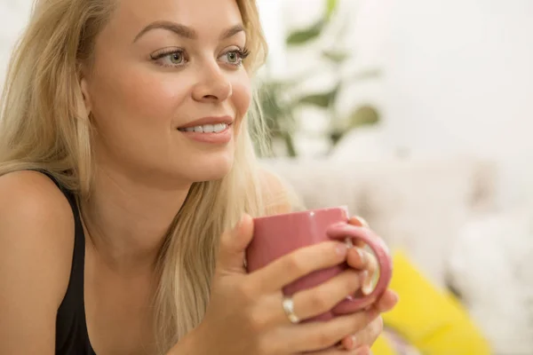 Close up of a stunning young woman smiling looking away relaxing having a cup of coffee dreaming thinking thoughtful beauty sexy gorgeous blondie lifestyle leisure recreation morning breakfast city