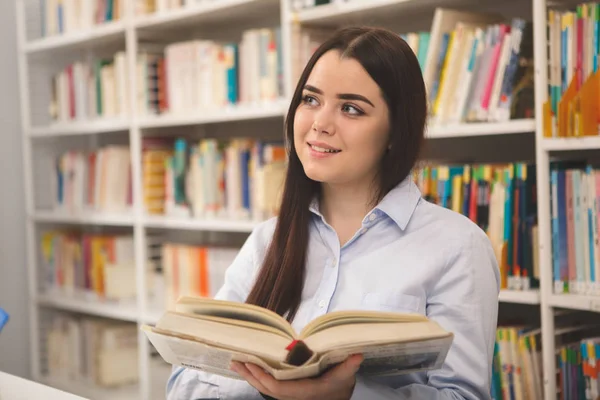 コピー スペース 図書館で本を読みながらうっとりと 離れて見て 笑って幸せな素敵な女 女子学生はキャンパスの図書館で読書を楽しんでいます 陽気な女性が書店で買物など — ストック写真