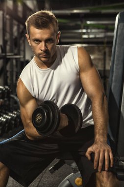 Yoğun eğitim. Şiddetle spor salonu dumbell ağırlık mı kamera isteyen ciddi genç yakışıklı bir adam dikey çekim Pompa kas vücut pazı spor motivasyon yaşam tarzı kavramı demir
