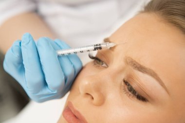 Kadın ona müşteri karşısında botox enjeksiyon yapma profesyonel bir güzellik uzmanı, yakın çekim. Güzel kadın klinik estetik dolgu maddeleri kozmetik şırınga yüz muamele 