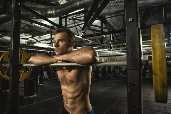 Preparing for the lift. Handsome young athletic shirtless man with hot sexy strong toned and fit muscular body looking away thinking resting at the gym motivation sports workout activity copysapce