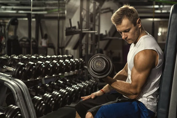 Feel the biceps burn. Muscular young man working out at the gym doing biceps curls with dumbbells weightlifting bodybuilding pumping iron strength sports fitness health masculinity concept copyspace