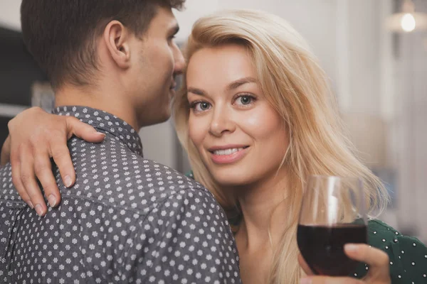 美しい若い女性 カメラに笑顔 台所で彼女の男を受け入れます 愛情のあるカップルを抱いて ワインを飲んで 周年を楽しんでします 乾杯の概念 — ストック写真