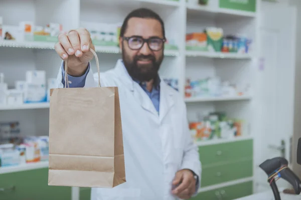 Happy Handsome Male Pharmacist Smiling Joyfully Holding Out Paper Bag — Stock Photo, Image