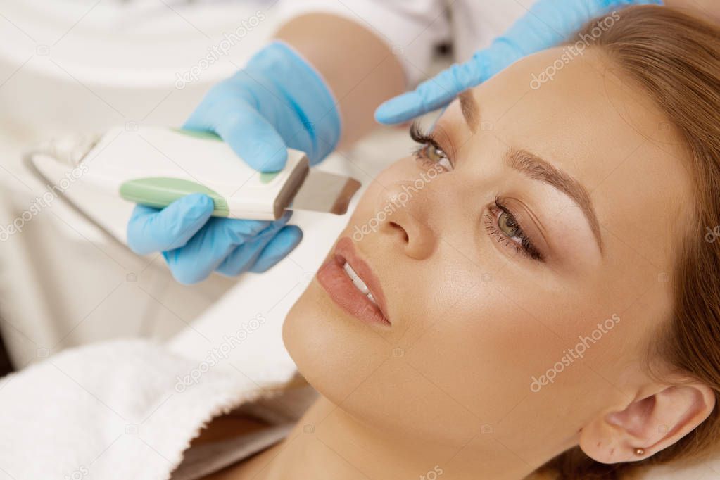 Cropped close up of a beautiful young woman having ultrasound cleansing treatment facial procedure by professional cosmetologist at beauty salon spa center skincare youth pampering smooth ultrasonic