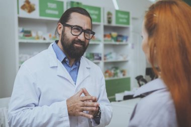 Neşeli erkek eczacı kadın müşteri ilaçları eczaneden satın almak yardım. Sakallı kimyager eczanede, çalışma tıbbi vererek hastaya tavsiye ederiz. İletişim, tıbbi bakım kavramı