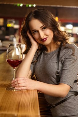 Kendi şirket içinde mutlu. Çekici bir genç kadın barda şarap alıyor dikey portresi seductively kameraya gülümseyen