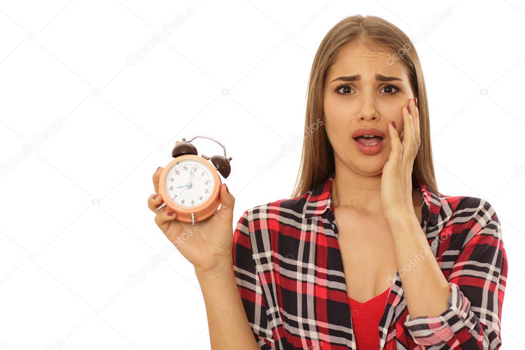 Young woman looking terrified screaming with her hand to her face holding alarm clock isolated on white copy space. Time management, timing, being late concept. Beautiful woman looking shocked