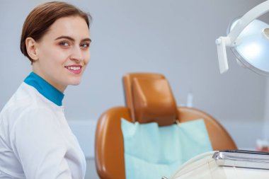 Onun omuz üzerinden kameraya gülümseyen çekici kadın doktor. Profesyonel diş hekimi sevinçle, kopya alanı gülümseyerek onu hasta için diş kliniğinde bekliyor. Feminizm, başarı, kadın kavramı