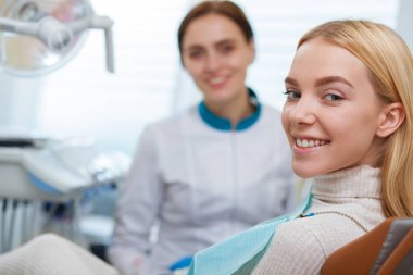 Muhteşem mutlu kadın kameraya gülümseyen, diş sandalye, kopya alanı oturan mükemmel sağlıklı dişlere sahip. Neşeli kadın ve onun dişçi klinikte muayene sonra sevinçle gülümseyen. Diş Hekimliği