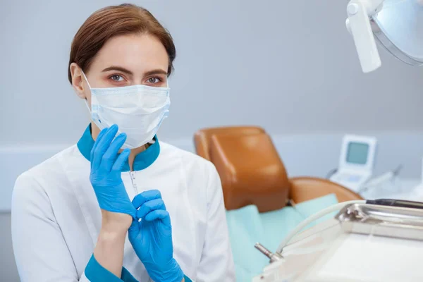 Lastik eldiven üzerinde koyarak profesyonel hekimi muayene için hazırlanıyor. Kadın doktor üniforması giyen medikal eldiven ve maske, kopya alanı içinde. Meslek, iş, sağlık kavramı