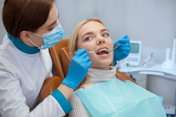 Tıbbi maske takıyor, Bayan hasta, kopya alanı diş inceleyerek profesyonel diş hekimi. Ortodontist müvekkili ile çalışma. Diş check-up olan güzel bir kadın. Profesyonellik kavramı