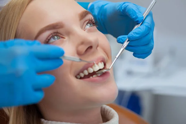 Güzel bir mutlu kadının gülümseyen, dişlerini profesyonel diş hekimi tarafından muayene alınırken kapatın. Diş check-up diş hekimleri ofiste sahip çekici bayan hasta. Gülümseme, kavram beyazlatma