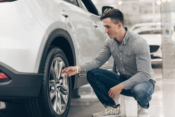 Joven comprando coche nuevo en el concesionario — Foto de Stock