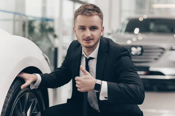 Atractivo hombre de negocios que compra un automóvil nuevo en el concesionario — Foto de Stock