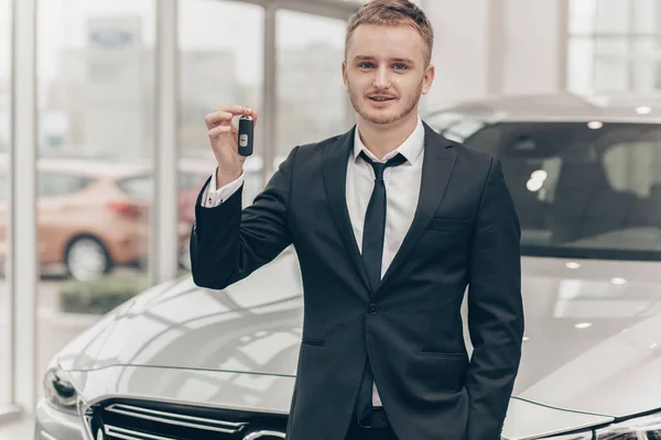 Atractivo hombre de negocios que compra un automóvil nuevo en el concesionario — Foto de Stock