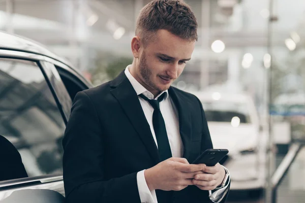 Atractivo hombre de negocios que compra un automóvil nuevo en el concesionario — Foto de Stock