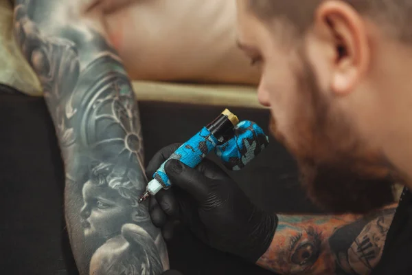 Bearded tattooist making tattoos on body of his client — Stock Photo, Image