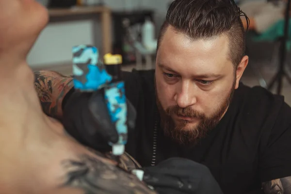 Bearded tattooist making tattoos on body of his client — Stock Photo, Image