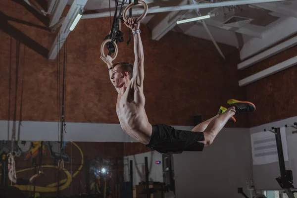 Muskulös manliga crossfit idrottsman tränar på Gymnastringar — Stockfoto