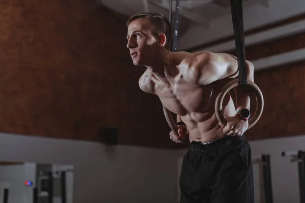 Atleta crossfit maschile muscolare che lavora sugli anelli ginnici — Foto Stock