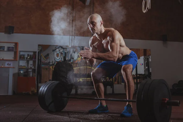 Forte atleta crossfit masculino exercitando com barra pesada — Fotografia de Stock