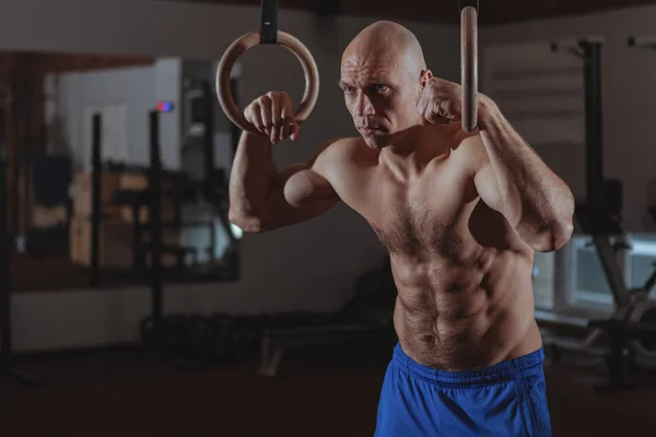 Musculoso atleta crossfit masculino haciendo ejercicio en anillos gimnásticos —  Fotos de Stock