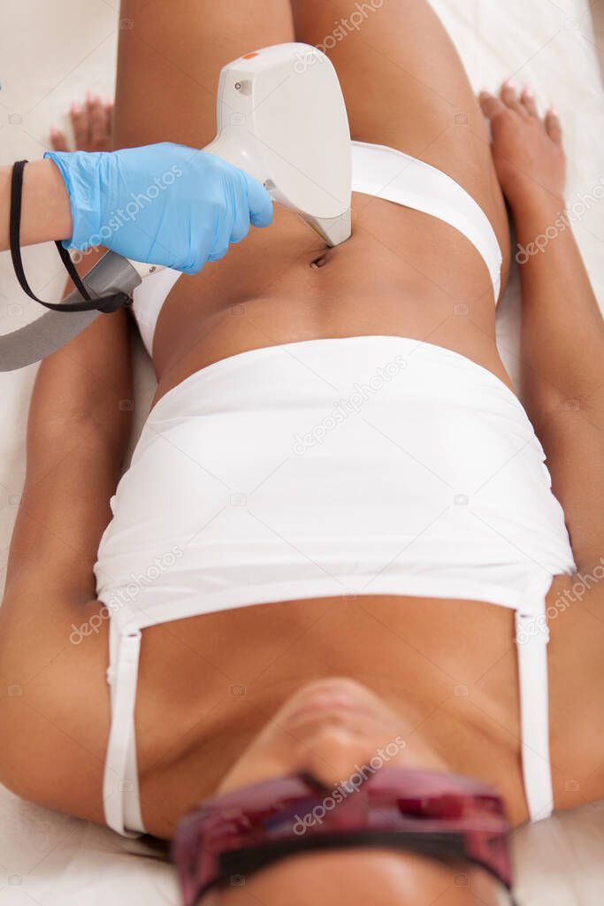 Cropped vertical shot of African woman getting laser hair removal on her stomach