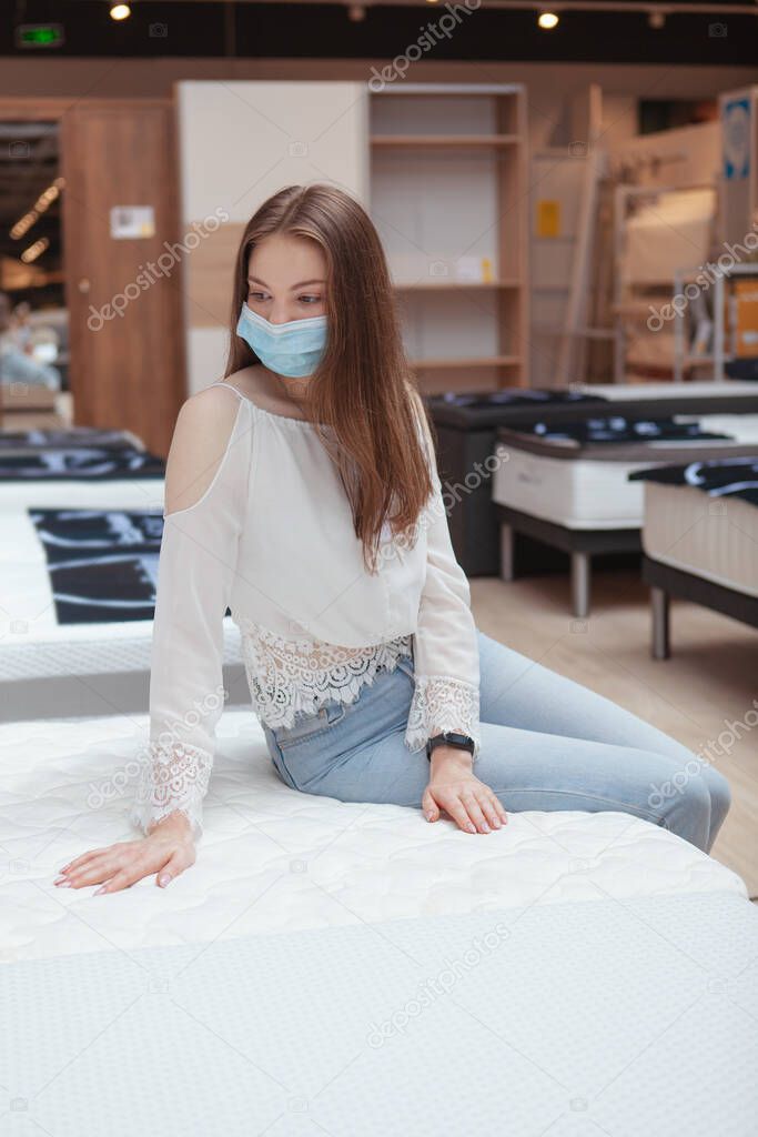 Vertical shot of a woman in protective face mask shopping for orthopedic bed