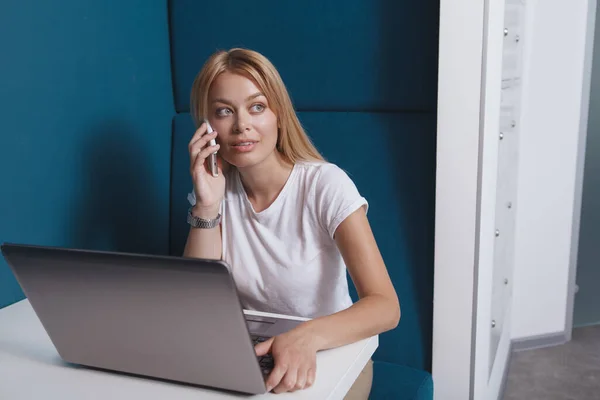 快乐美丽的女人在电话里聊天 在现代的工作空间里用笔记本电脑工作 — 图库照片