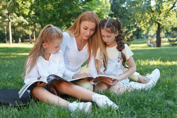 Atraktivní Mladá Žena Čtení Knihy Pro Své Studenty Sedí Trávě — Stock fotografie