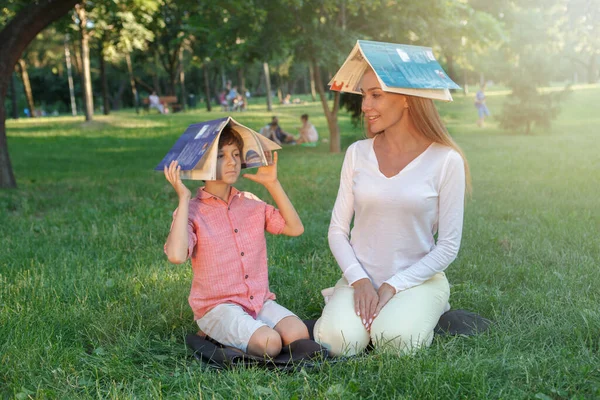 かわいい男の子は彼の先生と楽しみを持っています 公園で彼らの頭の上に本を身に着けています — ストック写真