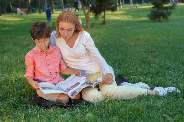 美しい若い女性教師小さな男の子 彼を助ける本を読む — ストック写真