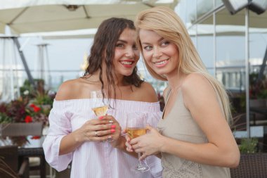 Çatı katındaki bir partide sohbet eden iki güzel kadın.