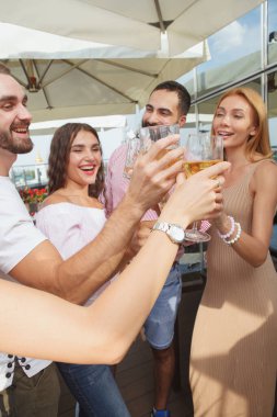 Çatıdaki partide kadehleri tokuşturan bir grup arkadaşın dikey görüntüsü.