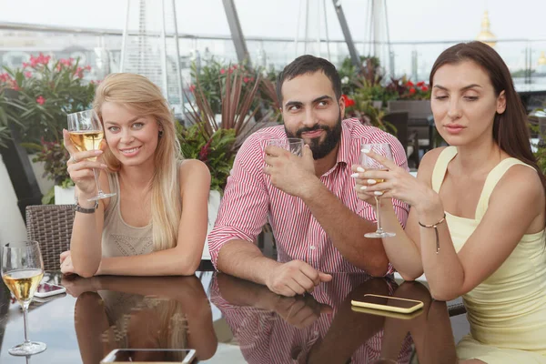Cheerful friends enjoying drinking together at rooftop bar