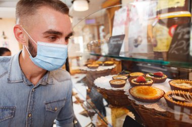 Pastaneden alışveriş yaparken tıbbi maske takan bir erkek müşterinin fotoğrafını çek.