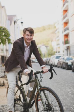 Orta yaşlı, mutlu, gülümseyen, bisikletinin üstünde oturan bir adamın dikey şortu.