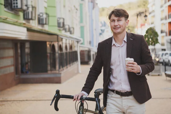 매력적 남자가 자전거를 시내를 산책하면서 커피를 즐긴다 — 스톡 사진