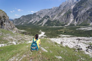 Uzun yürüyüşe çıkan kimse dağ panorama önünde oturuyor