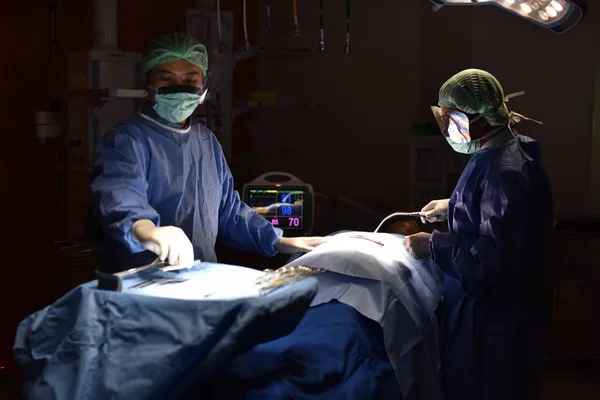 Team surgeon at work in operating room. Surgical light in the operating room. Preparation for the beginning of surgical operation with a cut. The surgeon is performing surgery on the patient.