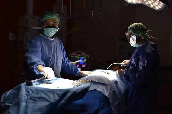 Team surgeon at work in operating room. Surgical light in the operating room. Preparation for the beginning of surgical operation with a cut. The surgeon is performing surgery on the patient.