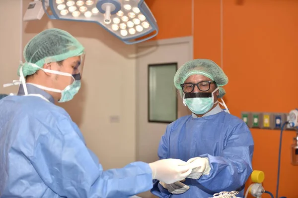 Team surgeon at work in operating room. Surgical light in the operating room. Preparation for the beginning of surgical operation with a cut. The surgeon is performing surgery on the patient.