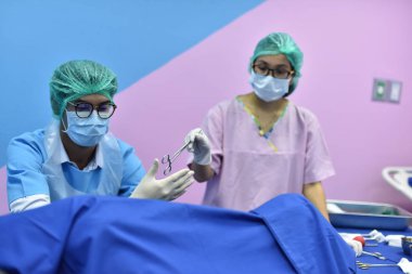 Ekip cerrahı ameliyathanede. Ameliyathanede cerrahi ışık. Ameliyat için hazırlıklar bir kesikle başlıyor. Cerrah hastayı ameliyat ediyor..