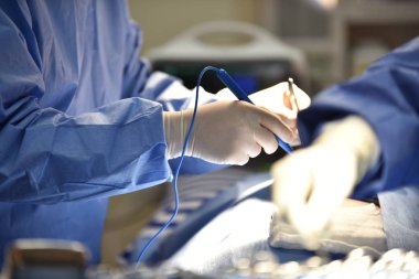 Ekip cerrahı ameliyathanede. Ameliyathanede cerrahi ışık. Ameliyat için hazırlıklar bir kesikle başlıyor. Cerrah hastayı ameliyat ediyor..