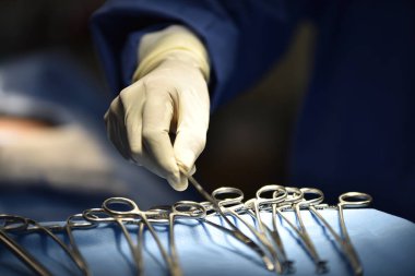 Ekip cerrahı ameliyathanede. Ameliyathanede cerrahi ışık. Ameliyat için hazırlıklar bir kesikle başlıyor. Cerrah hastayı ameliyat ediyor..